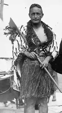 Jones standing with a taiaha (weapon), wearing traditional Māori clothing