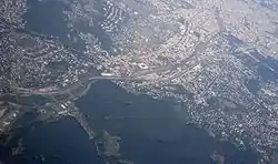 Aerial view of Penzing with Otto-Wagner-Spital near the top of the photo (three rows of big buildings), square-shaped Gerhard Hanappi Stadium downwards from it, and Baumgarten between them, with its sizable Baumgartner Cemetery.