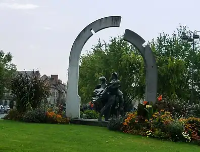 The flowery heart of the traffic circle, with a sculpture of two people overlooked by a two-part arch.