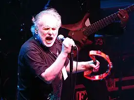 Brown playing tambourine onstage and singing into a microphone