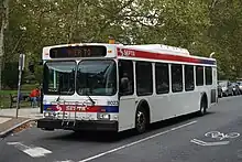 alt2=A white bus passes down a street.