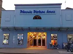 Plain façade, painted pale blue, with an awning