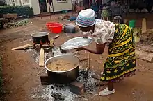 Image 7A Tanzanian woman cooks Pilau rice dish wearing traditional Kanga. (from Tanzania)