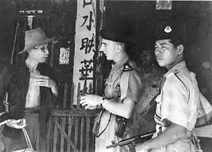 Two armed police officers questioning an elderly man