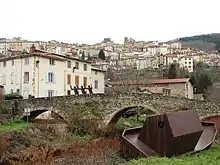 Densely-populated area across a stone arch bridge