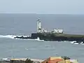 The lighthouse in Praia Harbour with a tiny view of the city