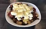 A breakfast poutine with hollandaise sauce and bacon.