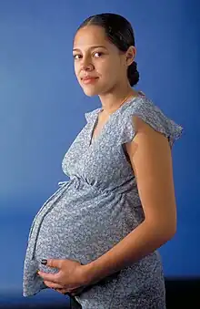 Young pregnant woman wearing early 21st century maternity blouse