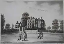 Burnt-out shell of a house in the background with five people standing in the foreground gazing at it