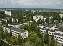 Wide shot image of Pripyat, Ukraine featuring an abandoned city square as well as various foliage.