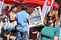 A woman with a Proletären newspaper with a stand used by the Communist Party during the Hammarkullekarnevalen [sv] in 2018.