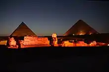 A complex of ruins, including two pyramids and the statue of the Sphinx.