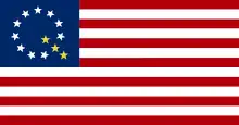 A modified version of the American flag with ten white stars and three gold stars forming a letter Q in the canton