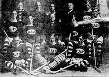 Black and white team photo of players in uniform sitting on chairs