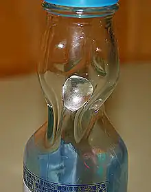 A Codd-neck bottle of Ramune, with the glass marble stopper inside its chamber after the bottle was opened