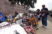 Mourners lay flowers and tributes in front of the Reagan Library's sign.