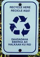 A rectangular sign with rounded corners, text about recycling, and the recycling symbol