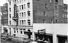 Black and white photo of a five-storey brick building with a large sign for The Leader-Post hanging from the fourth to second storey