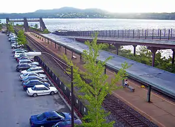 A covered railway station platform with two tracks next to a wide river