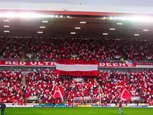 Photograph people dressed in red and white in a stadium stand