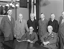 Members of Reid's cabinet gathered around a table in an office.