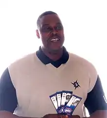 alt=A man, wearing a black and white shirt, is holding several tickets in his hands.