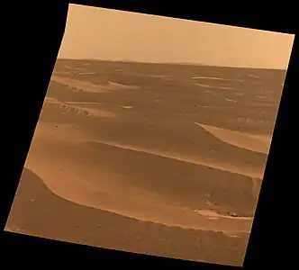 The rim of Bopolu crater is visible on the horizon of this March 2010 image taken by the Mars rover Opportunity; Bopolu is 65 kilometers (40 miles)  away, when the rover was making its traverse to the closer Endeavour crater.