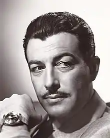 Robert Taylor, looking off-camera with his hand near his chin