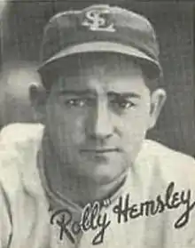 A man in a light baseball uniform and dark cap with "SL" on the center.