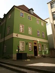 A green three-story house on a cobblestone street, typical of medieval German towns