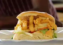 A close-up view of a personal-sized Gatsby sandwich prepared with calamari and chips