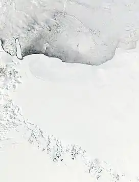 A wide expanse of ice covering the bottom two-thirds of the satellite image, and icy water covering the rest. There are dark mountains in the bottom-left.