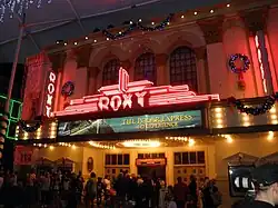 The Roxy Theatre's entrance decorated with Christmas lights and hollies; a marquee advertises the "Polar Express 4-D Experience" film.