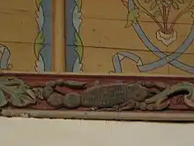 Photograph of a carved and painted beam depicting a scorpion