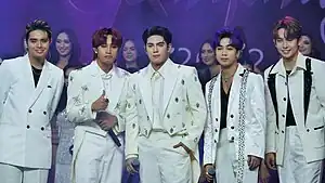 A group portrait of SB19 with each member wearing a white suit