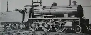 Side-and-front view of a 3-cylinder 2-6-0. The distinguishing feature is a full-width flat panel rising vertically above the front buffer beam to the level of the bottom of the smokebox door.