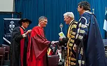 Sadoway, wearing a red robe, on a stage with other men wearing academic regalia