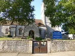 View from the entrance to a short path leading to a church building with an adjoined tower on the right.