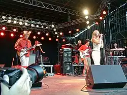 Photograph of the four male and two female members of the band Saint Etienne perform on a stage