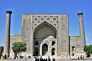 Front facade of the madrasa with some people in the foreground