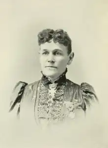 B&W portrait photo of a middle-aged woman with her hair in an up-do, wearing a dark blouse.