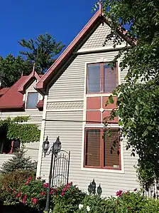 a) Scalloped ornamentation on gable apex, b) Vertical windows, c) Steep roofs, d) Spires