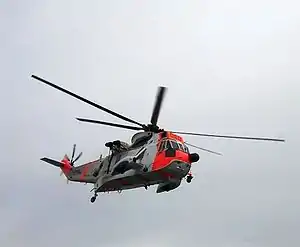 A red and white helicopter in the air.