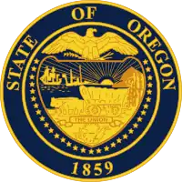 A navy blue seal with gold lettering and imagery. The seal contains a shield, supported by 33 stars and with an eagle with its wings spread on top; "STATE OF OREGON" is written above the eagle and "1859" appears below the shield. Within the shield appear a sun with its rays extending to two ships and a mountain and trees, two oxen pulling a covered wagon, and a ribbon containing "THE UNION".