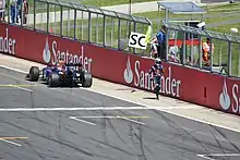 Sebastian Vettel walking away from his stricken car parked next to the pit wall