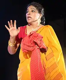 Photograph of Indian woman, who is acting in a red and yellow dress