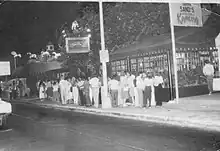 Black and white photo of establishment named Señor Frog's with people lined-up to get in, photo taken at night