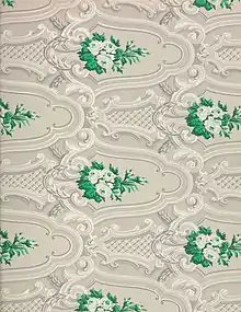 Detail of ornate wallpaper in a gray, white, and green design.