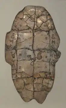 Tortoise plastron with divination inscription from the Shang dynasty, dating from the reign of King Wu Ding. The piece has complementary charges down the left and right sides. Cracks caused by applying a heat source to the reverse are numbered 1–6 on the left and 1–7 on the right. The outcome of the interpretation of these cracks is recorded at bottom right.