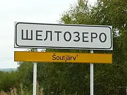 A sign on the P–19 Highway at the entrance to Shyoltozero, with the name in Russian and in Veps